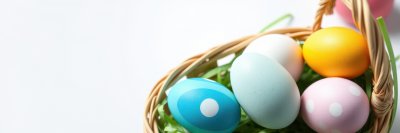 Colorful Easter eggs in a woven basket surrounded by green grass and soft lighting for spring celebration